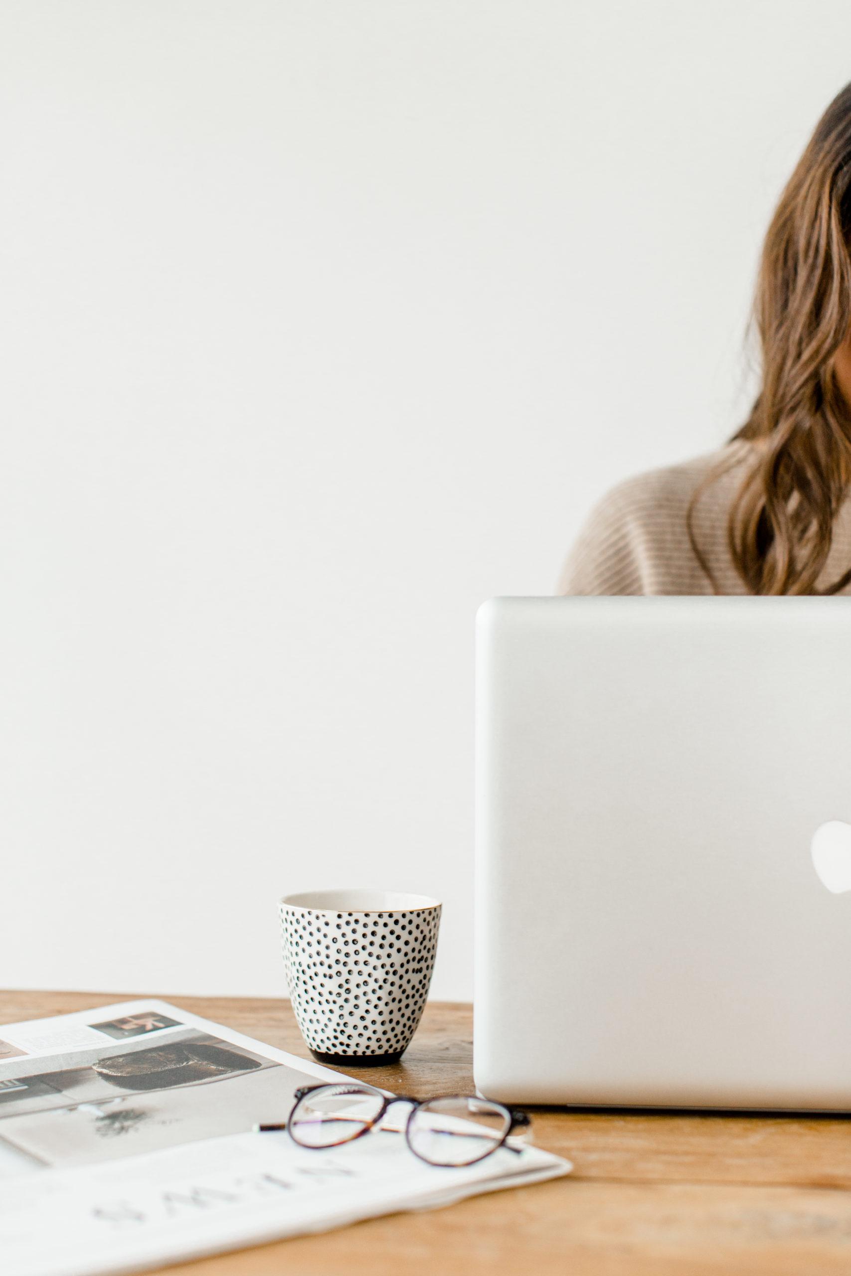 Frau arbeitet am Laptop mit Kaffeetasse und bindet Google Fonts ein